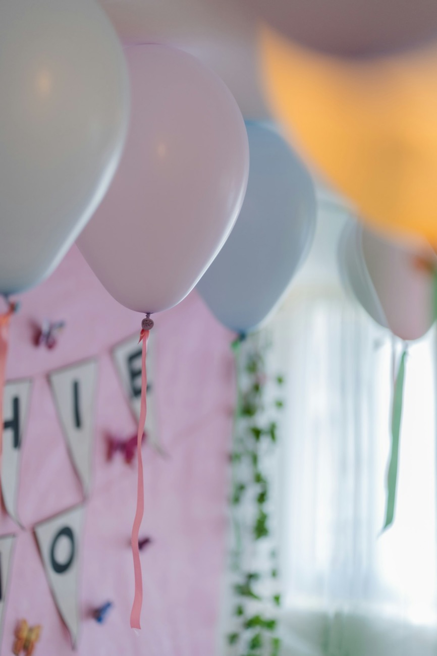 Balões em tons pastel e bandeirinhas numa festa de aniversário