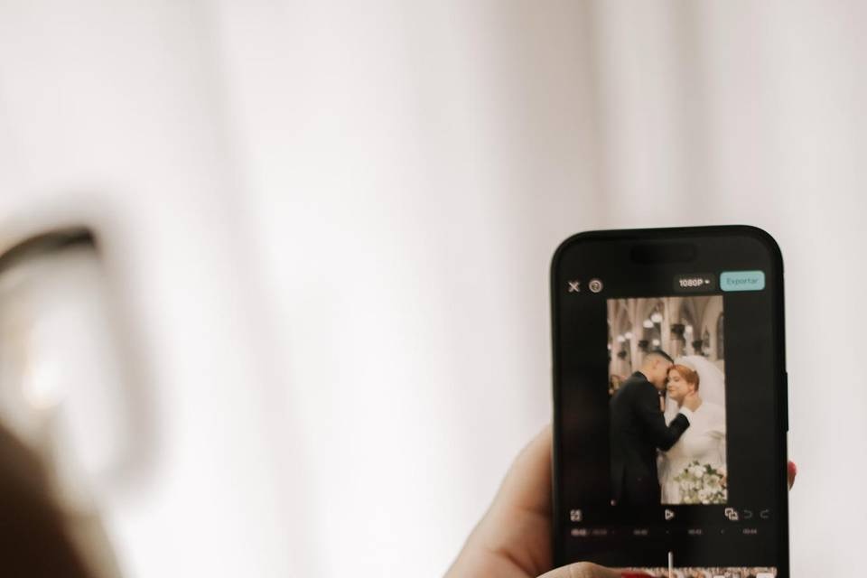 Mão segurando um celular que mostra a edição de um vídeo de casamento